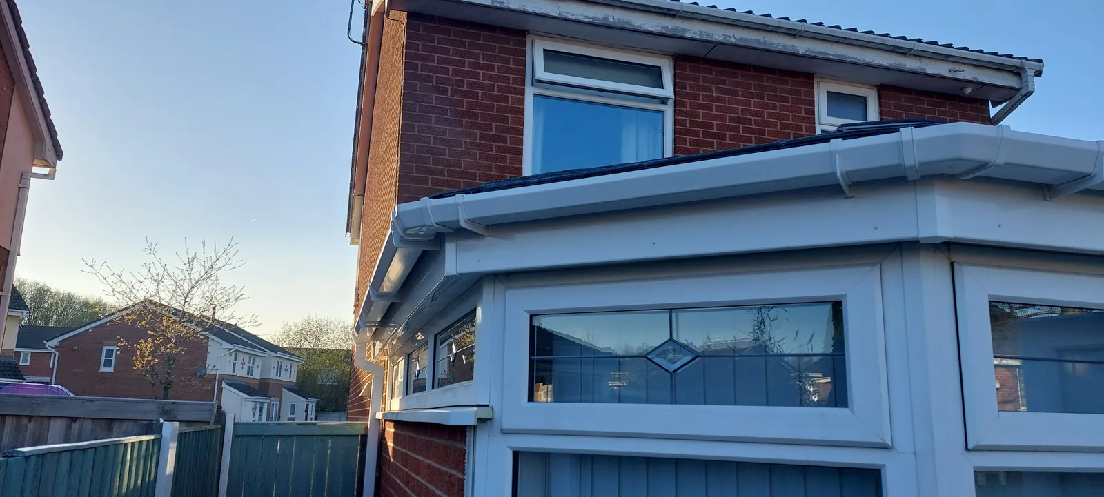 Bay window and white uPVC fascia detail on a red-brick house with a tiled bay roof.