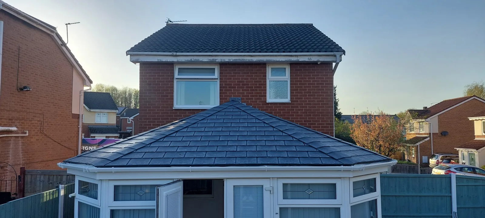 Conservatory with new slate-effect tiled roof at the rear of a red-brick semi-detached house.